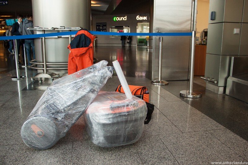 Завернутый чемодан. Упаковка багажа в аэропорту. Упаковка чемоданов в аэропорту. Упаковка багажа. Упаковка сумки в аэропорту.