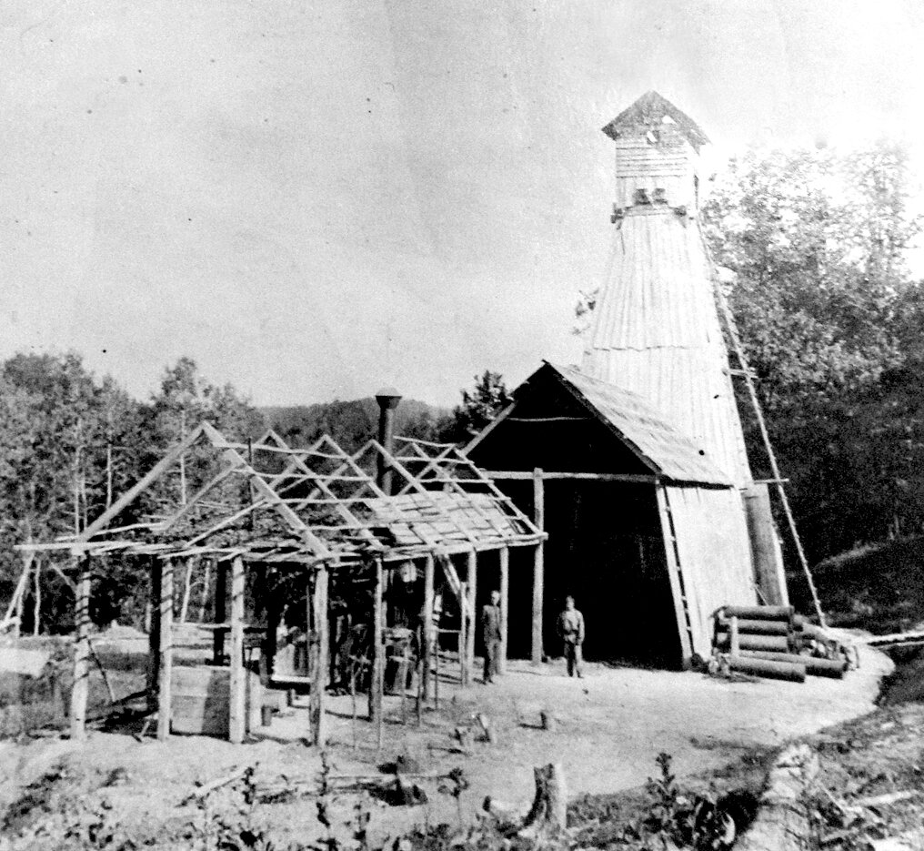 Установка буровой скважины ильского нефтяного промысла. Рядом – возведение временного строения.