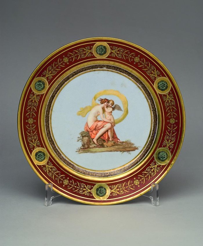Тарелка десертная «Амур, ухаживающий за матерью» из «Олимпийского сервиза». Франция, Севрская мануфактура, 1804-1807. Художник-керамист: Жакото Мария-Виктория, золотильщик: Констан Шарль Луи. Диаметр: 23,5 см.