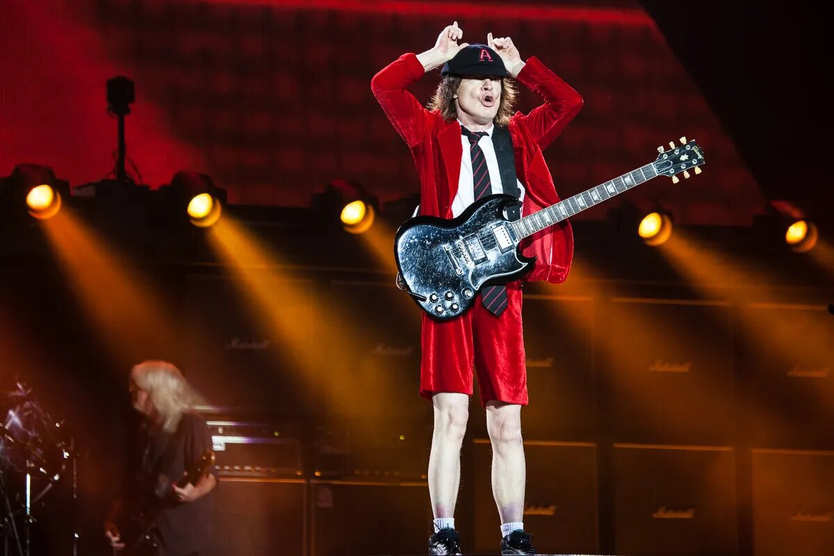 Гитарист AC DC В шортах. AC DC Angus young молодой. Гитарист Эйси ДИСИ. AC DC Angus young 2021.