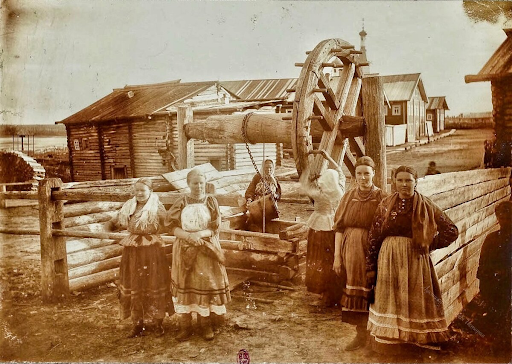 Женщины на фоне колесного колодца. Это рычажной вариант, а были еще «ступальные» колодцы, где внутри ступал человек, опуская и поднимая ведра с водой