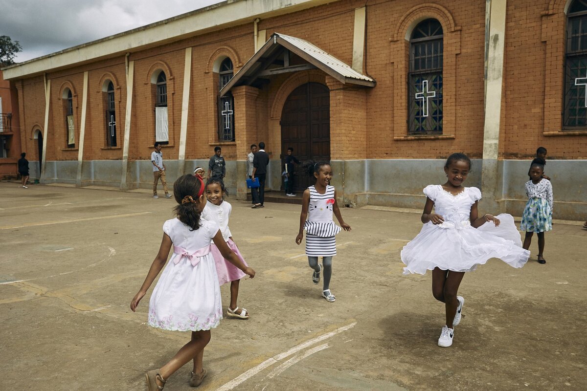 Дети играют возле церкви во время воскресной утренней службы в Римско-католической церкви в Мандросоа Ивато, Антананариву, Мадагаскар.