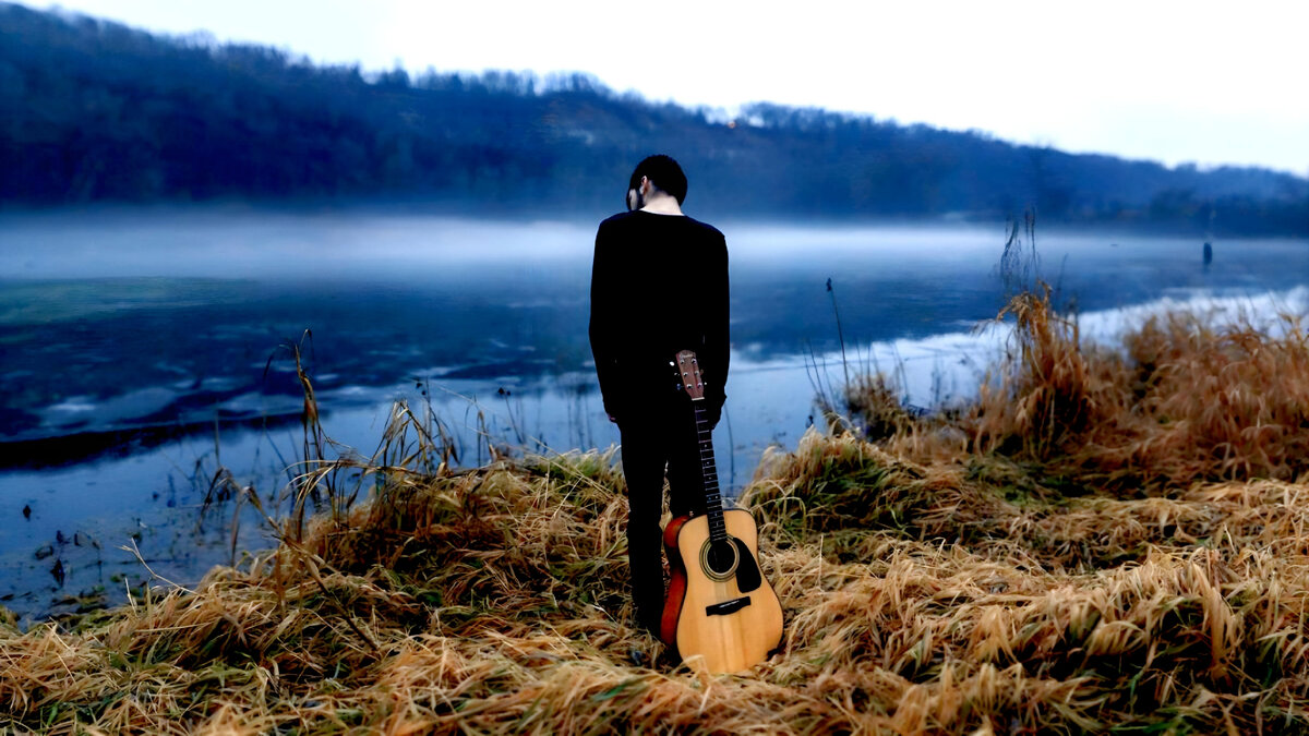 Грустный музыкант на берегу реки. Фото из открытых источников