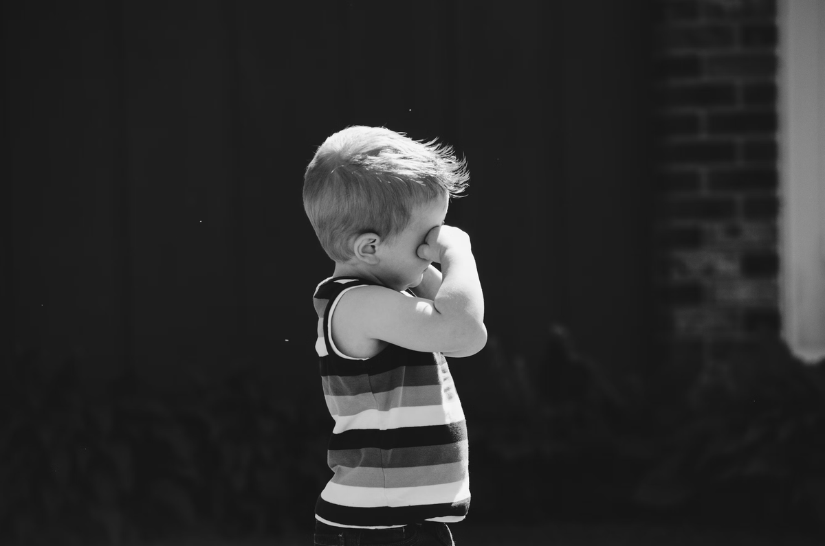 https://unsplash.com/photos/grayscale-photo-of-boy-covering-of-eye-while-standing-behind-concrete-wall-k0o-cw5Y_9s