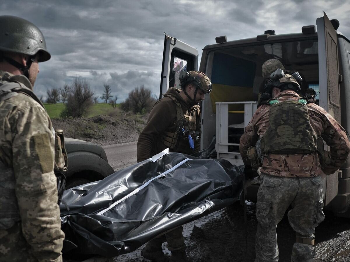    Украинские военные переносят тело погибшего в Донецкой области© AFP 2024 / SERGEY SHESTAK