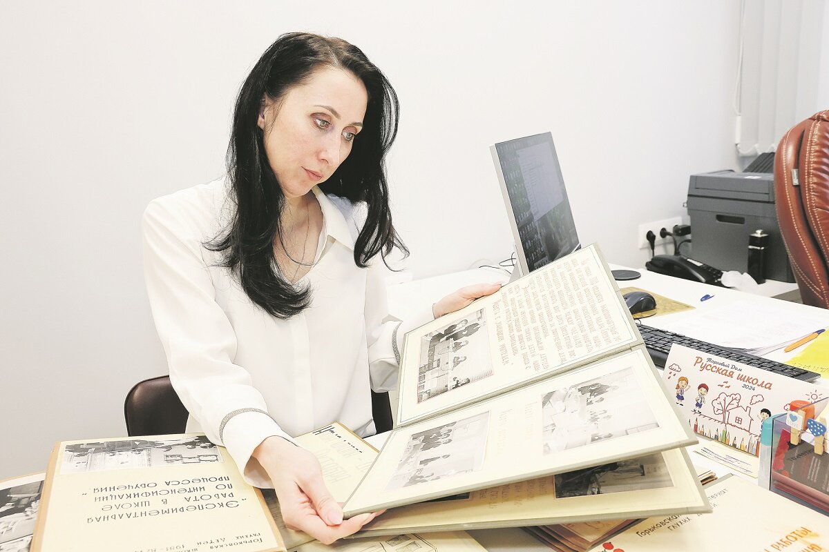    Директор школы Нина Поликарпова листает альбом с историческими фото