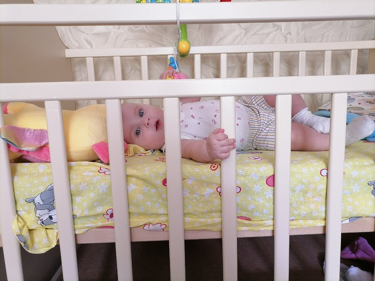 Играет в кроватке.