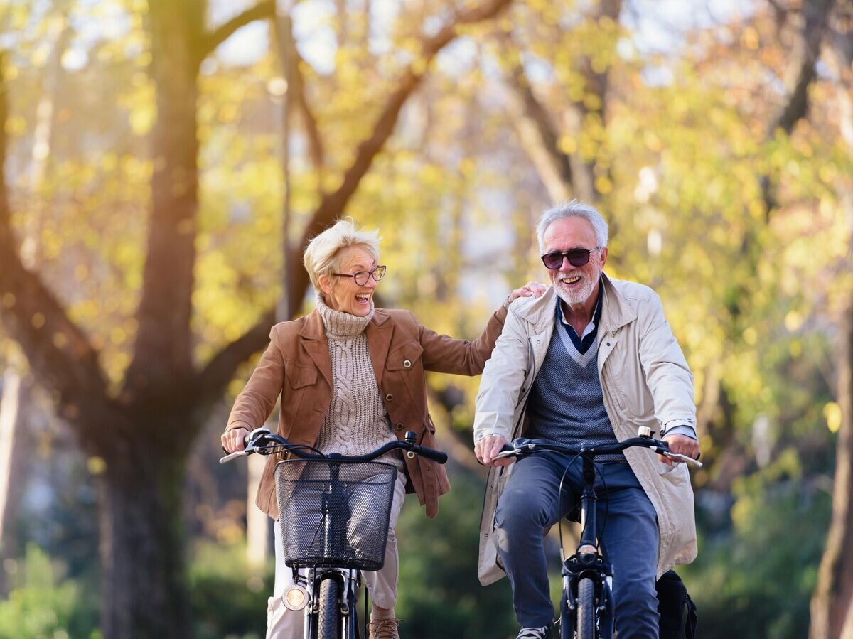    Пожилая пара катается на велосипедах в парке© iStock.com / Lordn