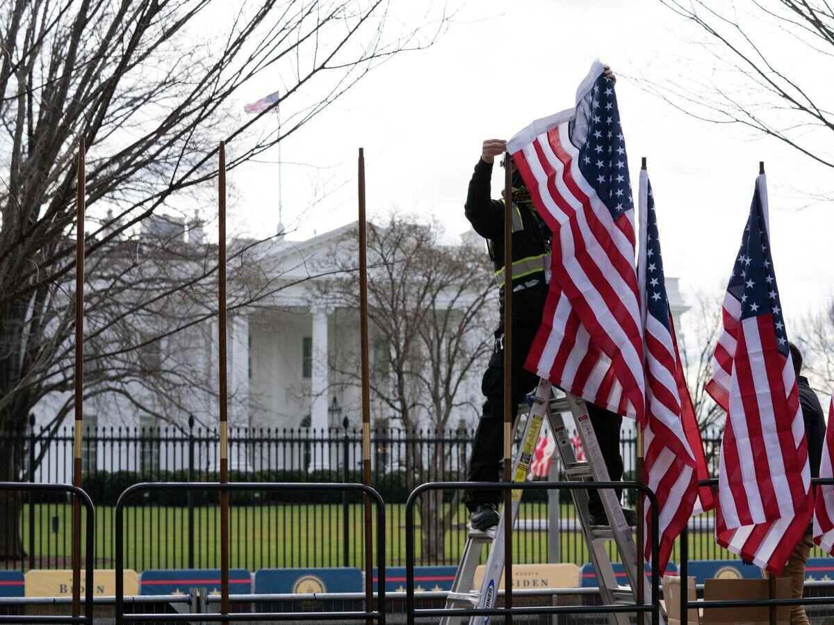    Рабочий устанавливает флаги возле Белого дома в Вашингтоне© AP Photo / Jose Luis Magana