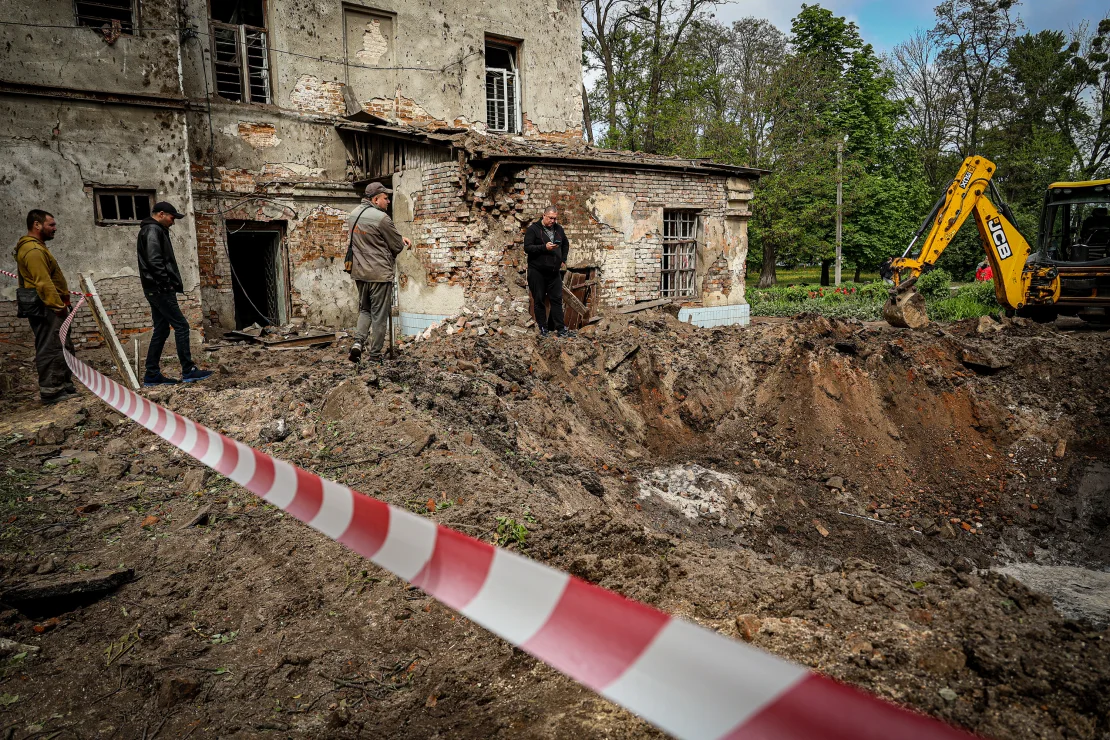 Рабочие коммунальных служб убирают последствия ночного ракетного обстрела в украинском городе Харькове 27 апреля.Stringer/Anadolu via Getty Images.