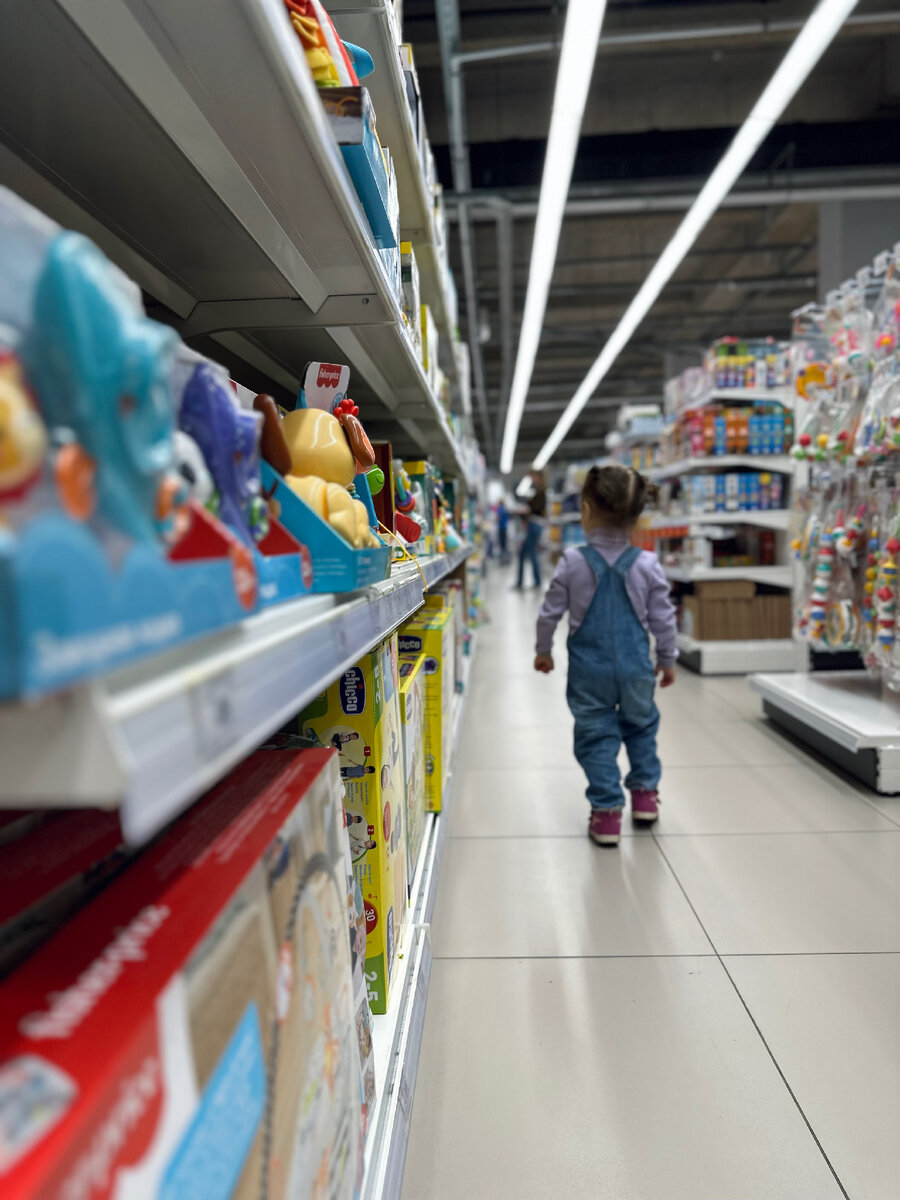 «Детский мир», дочка исследует витрины. По фото видно, что настрой у нее решительный.