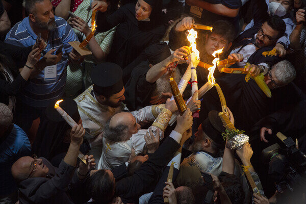 Греческий православный патриарх Иерусалима Феофил III (слева) держит свечи для христианских паломников во время церемонии зажжения Благодатного огня в храме Гроба Господня, Иерусалим, 2021 год / Ariel Schalit/AP   📷