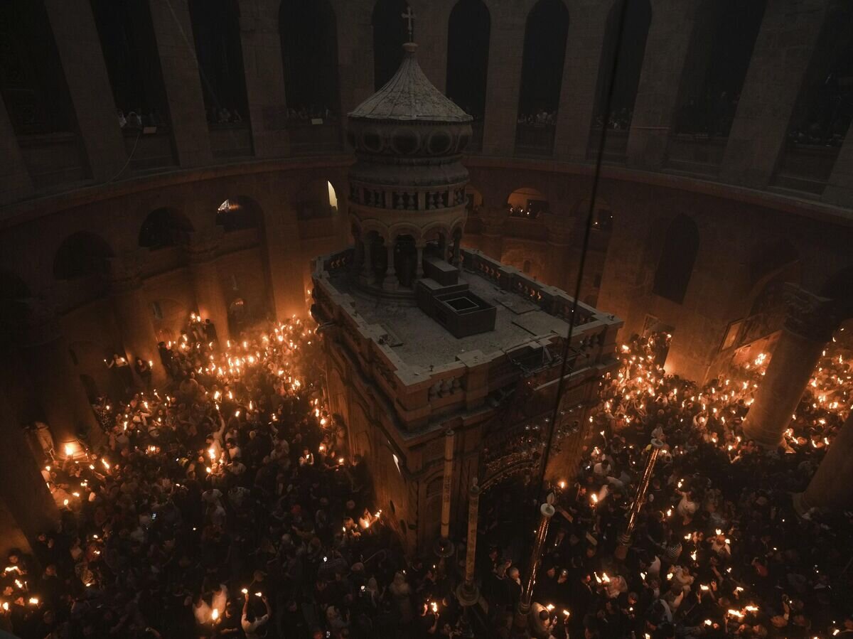    Паломники держат свечи во время церемонии схождения Благодатного огня в храме Гроба Господня© AP Photo / Mahmoud Illean