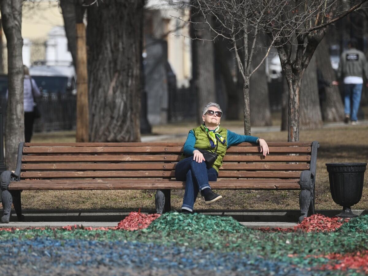    Женщина отдыхает на скамейке во время теплой погоды в одном из парков Москвы© РИА Новости / Кирилл Каллиников