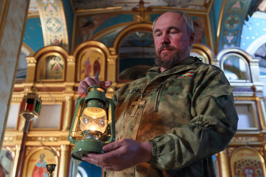 Военный священник во время доставки Благодатного огня из Иерусалима в храме Архистратига Михаила в ДНР - Фото: Дмитрий Ягодкин/ТАСС
