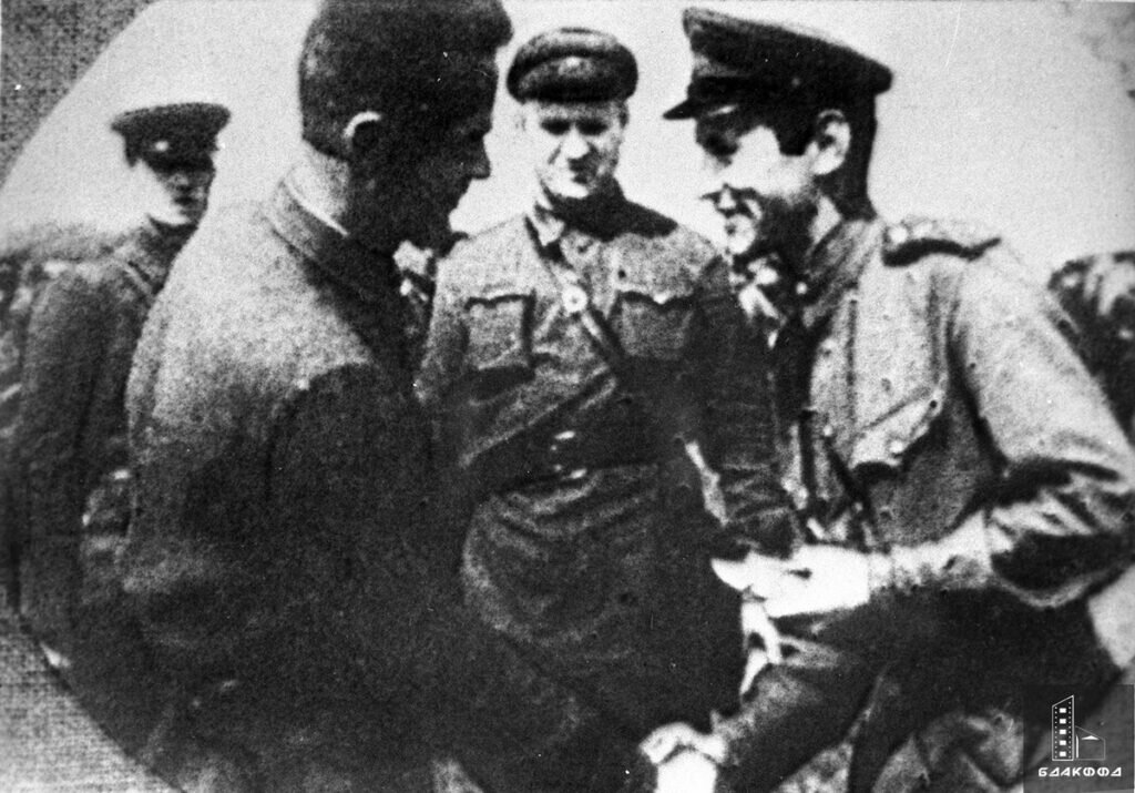 Заместитель начальника Белорусского штаба партизанского движения И. П. Ганенко (1-й слева) вручает медаль «Партизану Великой Отечественной войны» 1-й степени В. П. Цеслюку на вручении государственных наград в Лошице под Минском — одну из боевых кинохроник оператор записывал год назад именно в этих местах, ЦГАКФФД БССР, июль 1944 г. Довоенное кино СССР, во многом вышедшее из кинохроник Первой Мировой и Гражданской войн, дополнилось традициями съемок времен Великой Отечественной — и дало обширные всходы в белорусском советском послевоенном и суверенном кино и, что важно, телевидении, отпочковавшемся от кинопроизводства на пороге 1940-1950-х годов. Операторы видеохроники героической эпохи 1941-1945 гг. протоптали дорогу в том числе и множеству профессий и специальностей современного белорусского телевидения.