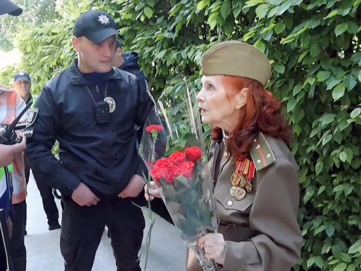    Сотрудники полиции Украины не пускают женщину возложить цветы к Вечному огню в Киеве. Кадр видео© Соцсети