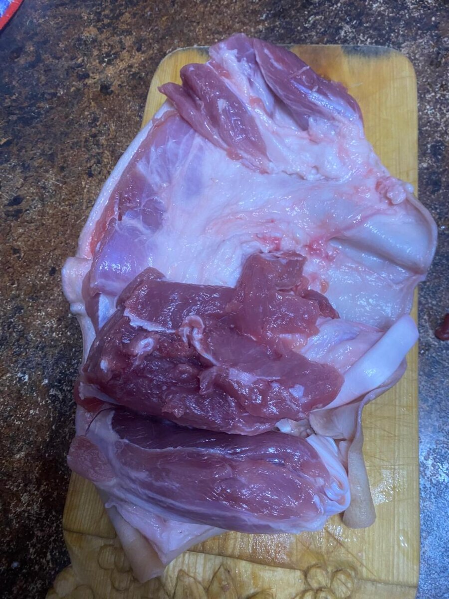 Вырезали кость и срезаем как бы лишнее мясо, чтобы потом его равномерно распределить по всей поверхности кожи рульки.