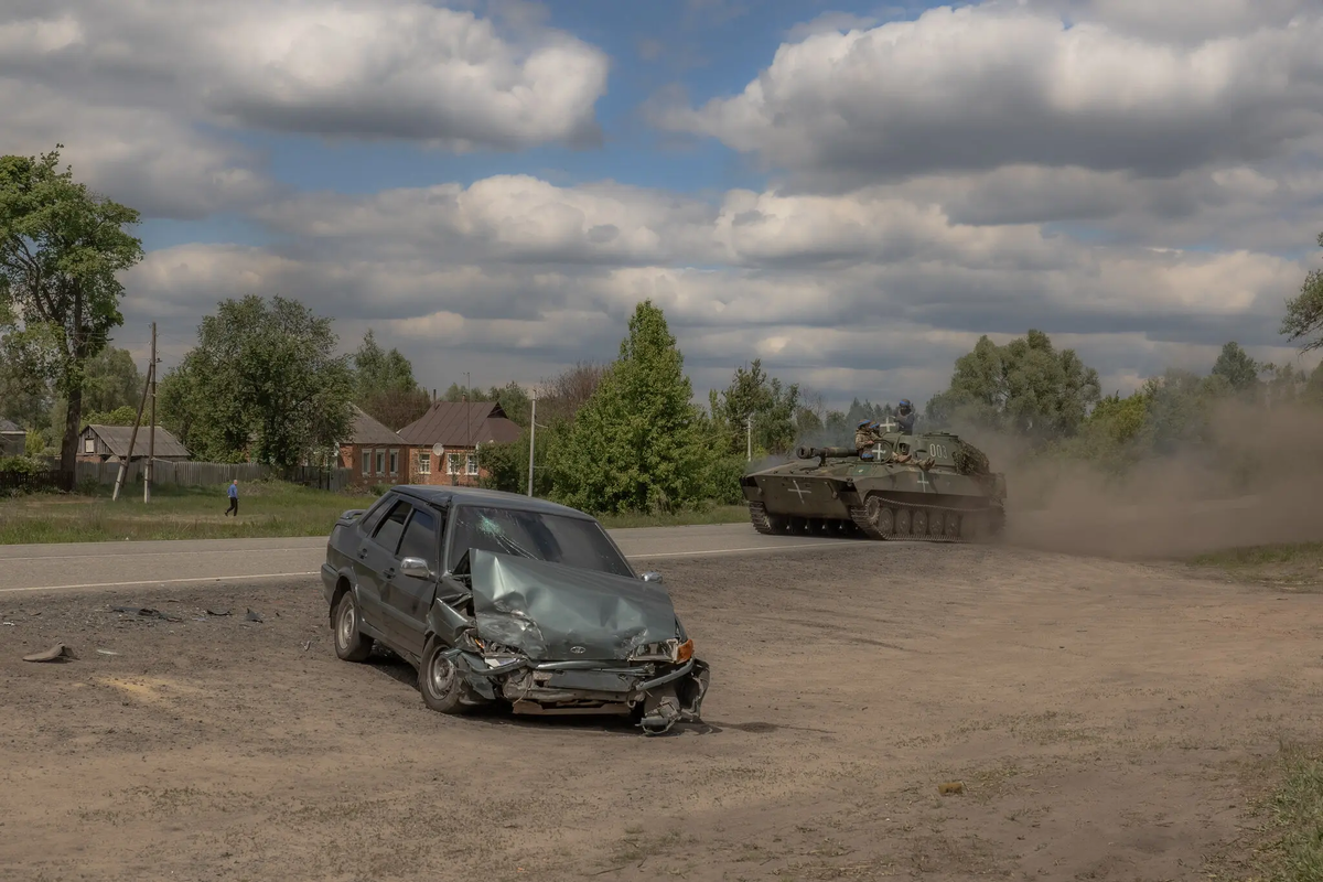 Украинский танк в воскресенье возле поврежденного автомобиля в Волчанском районе Харьковской области. Фото: Roman Pilipey/Agence France-Presse - Getty Images.