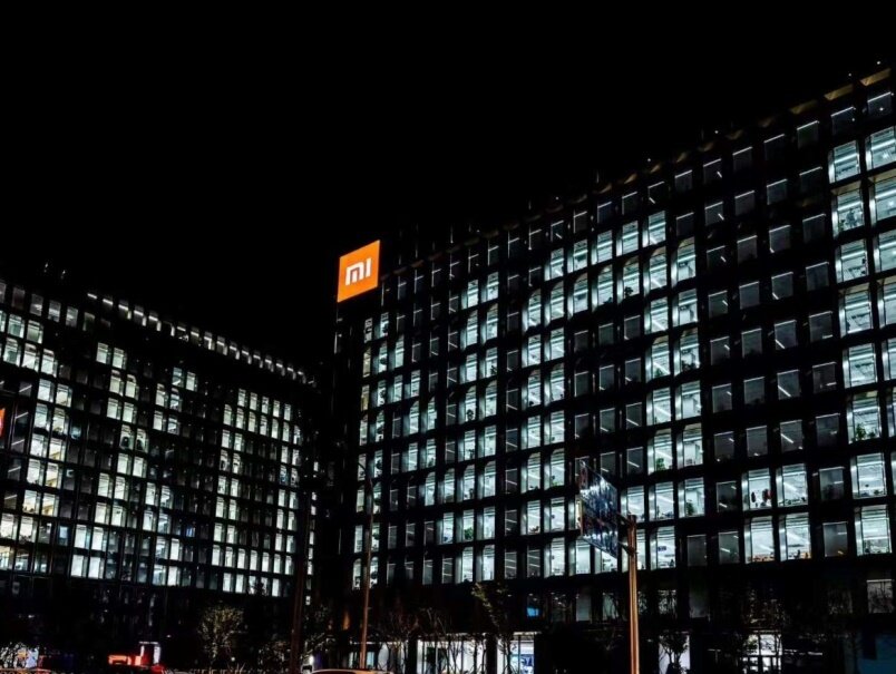 Эта реклама Xiaomi эффективно привлекает внимание ярко освещенным логотипом на фасаде здания, демонстрируя значительное присутствие и узнаваемость бренда даже ночью. 