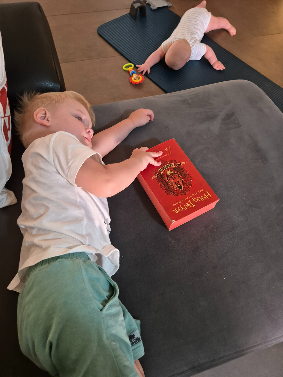 Уставший лежит на диване, листает книжку