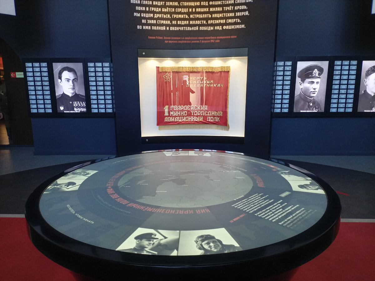 Центральный зал. Интерактивный стол на 4 посетителей. На заднем плане Знамя 1-го гвардейского минно-торпедного авиационного полка ВВС Балтийского флота