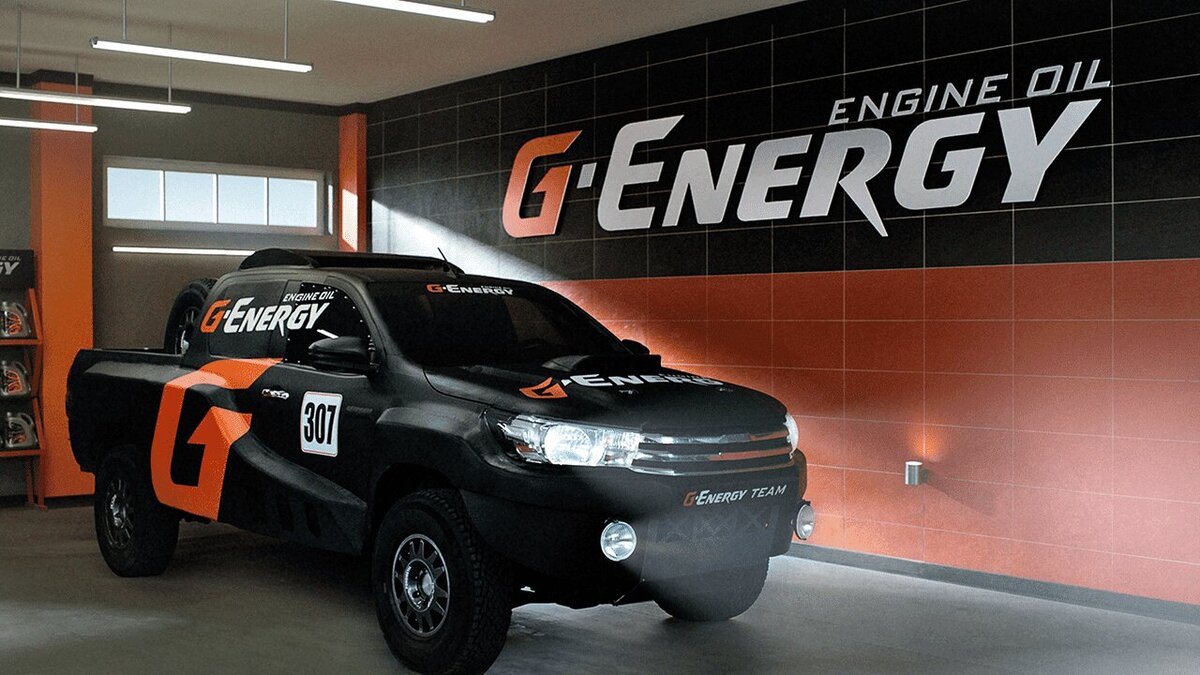 Эффективная реклама моторного масла G-Energy демонстрирует мощный внедорожник, обклеенный фирменными логотипами и номерами, стоящий в стильном гараже с брендинговой стеной, что подчёркивает высокое качество и производительность продукта. 
