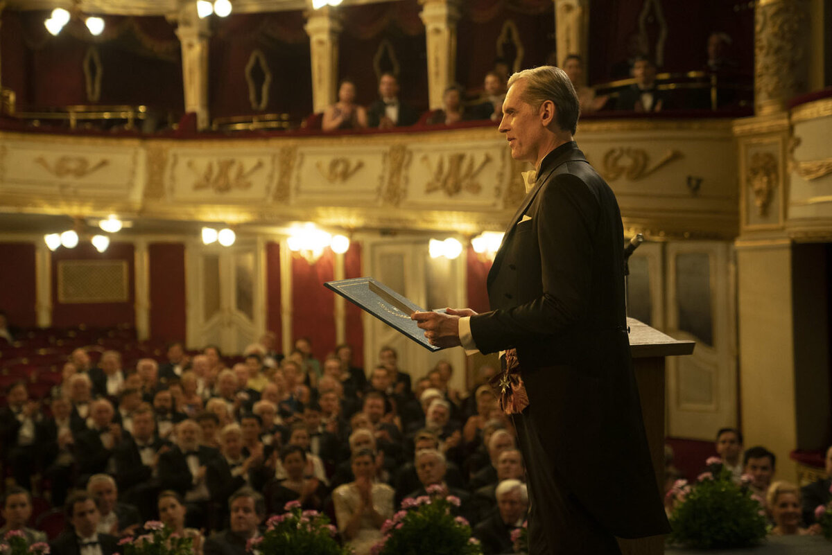 Кадр из начала фильма, где объявляют нобелевских лауреатов. Но тут имеет место историческая неточность - на самом деле лауреатов извещают заранее о решении Нобелевского комитета. И все сидящие в зале уже знают, кого пришли чествовать.  