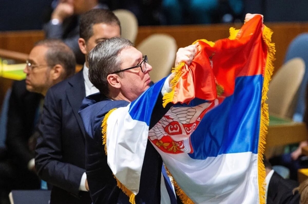    Президент Сербии Александр Вучич показывает флаг Сербии делегатам после голосования на Генассамблее ООН по учреждению международного дня в память о геноциде Сребрениц.