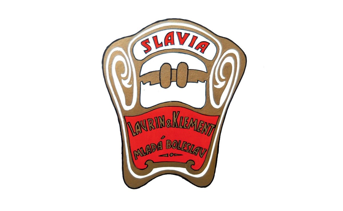    Через год после дебюта мотоцикла Slavia в 1899 году и начала экспорта продукции в другие страны, у фирмы появилась новая эмблема. Это был яркий, стильный значок с надписями Laurin & Klement и Mlada-Boleslav на алом фоне c золотым обрамлением.