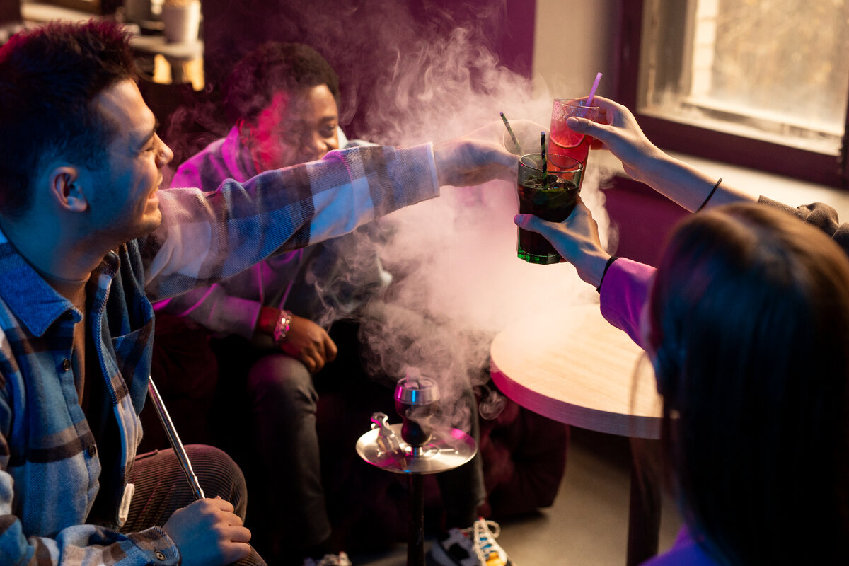 Группа людей отдыхает в заведении с кальяном