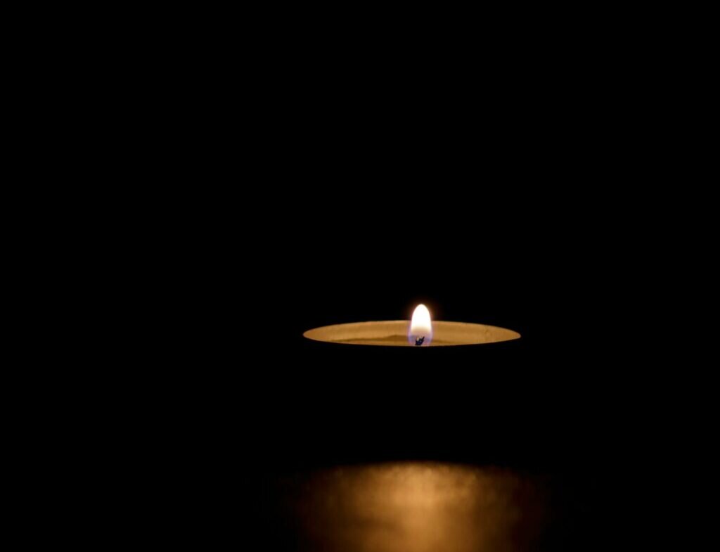    A lit tin candle in the dark conveying memorial, death, hope or darkness Екатерина Малаховская