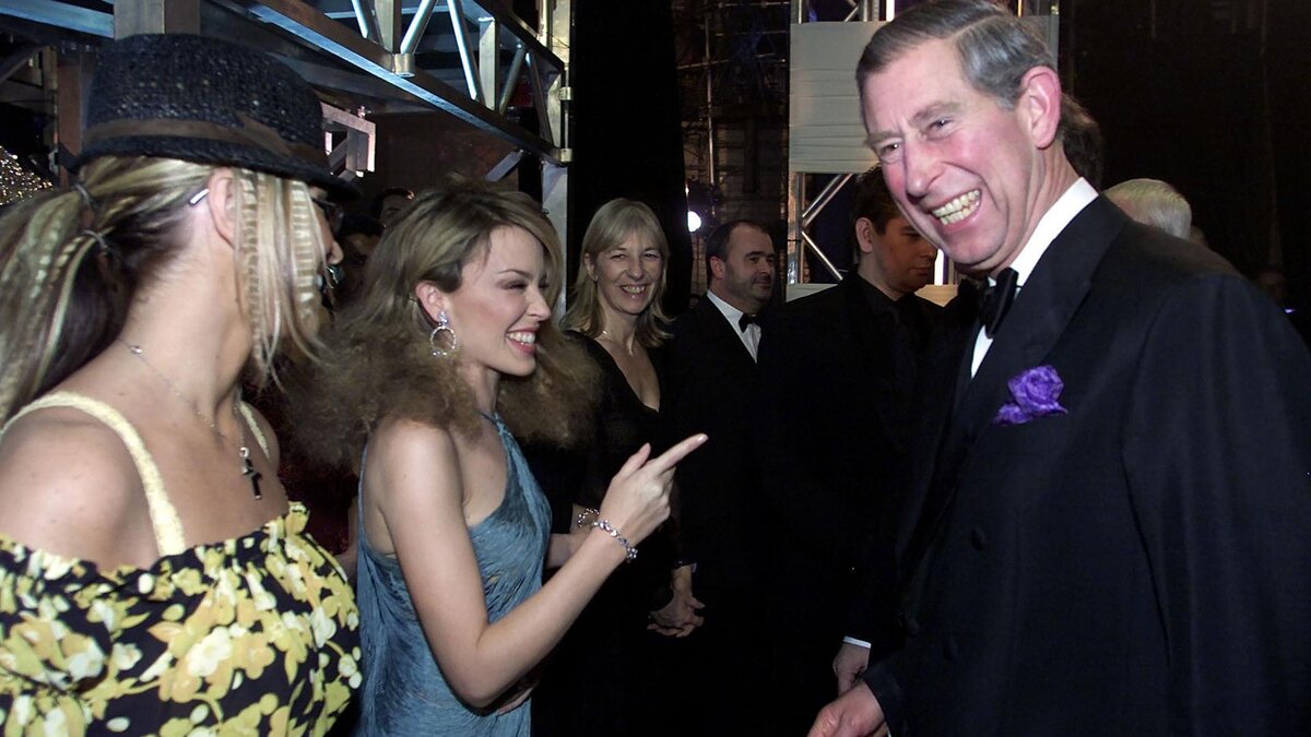 PA Images / Getty Images📷Принц Уэльский Чарльз (ныне король Карл III) во время знакомства с певицами Кайли Миноуг (в центре) и Анастейшей (слева) после Королевского эстрадного представления в театре «Аполло», 2002 год