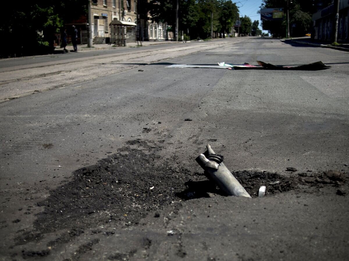    Фрагмент снаряда застрявший в асфальте после артиллерийского обстрела Луганска украинскими силовиками© РИА Новости / Валерий Мельников