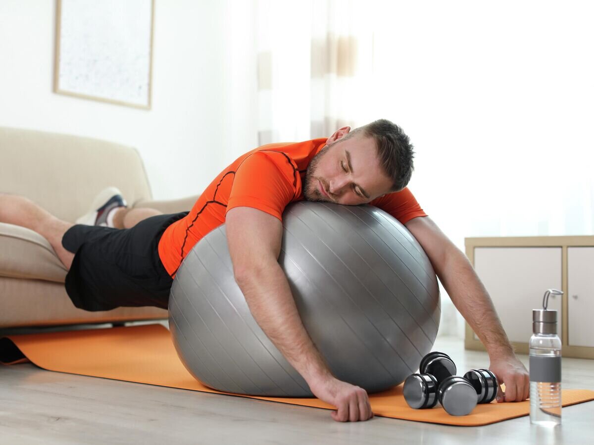    Ленивый человек со спортивным снаряжением дома © Depositphotos.com / Olga Yastremska