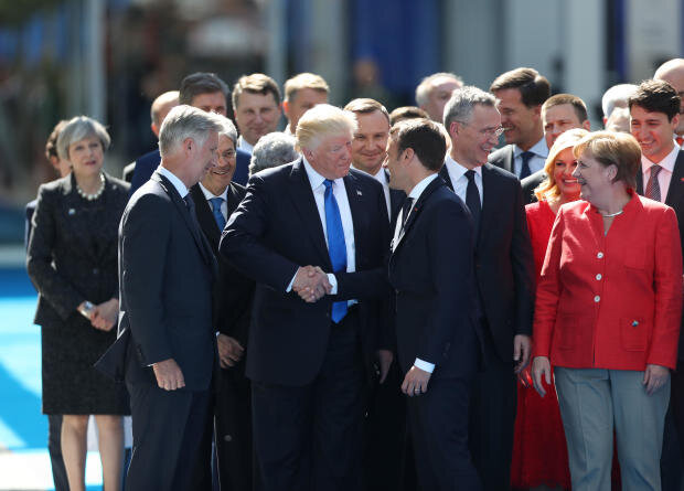 Президент Дональд Трамп (слева в центре) пожимает руку Эммануэлю Макрону, президенту Франции, в то время как другие мировые лидеры наблюдают за саммитом НАТО в Брюсселе в четверг, 25 мая 2017 года. ДЖАСПЕР ДЖУЙНЕН / BLOOMBERG ЧЕРЕЗ GETTY IMAGES