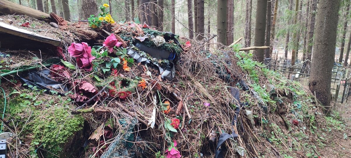 Созданная посетителями кладбища свалка из искусственных цветов. Между участками. Ленинградская область, Всеволожский район.