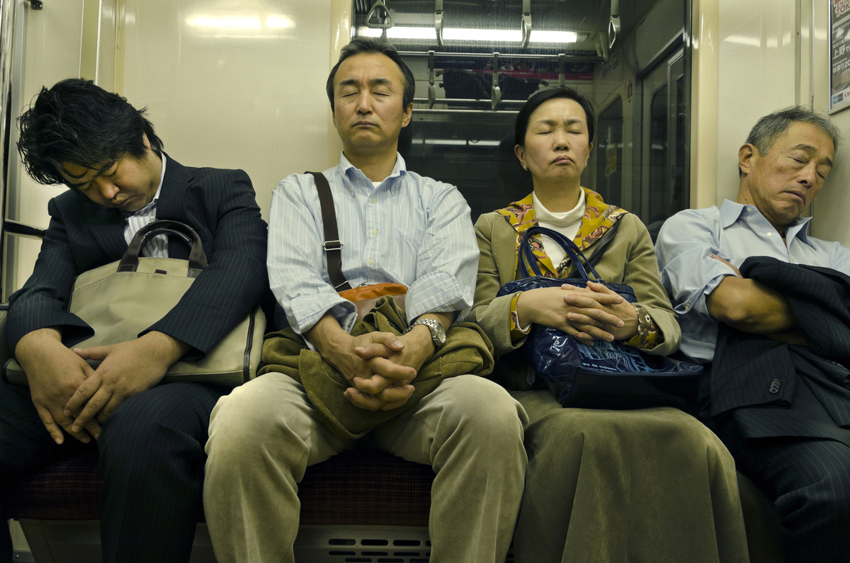 Фото из газеты Japan Times с подписью: "Погашаем долг за сон. Пассажиры спят в поезде, идущем в Токио"