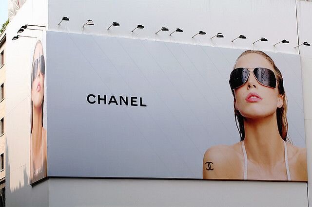 Эффективная наружная реклама Chanel привлекает внимание стильным изображением модели в солнцезащитных очках, подчеркивая элегантность и роскошь бренда. 