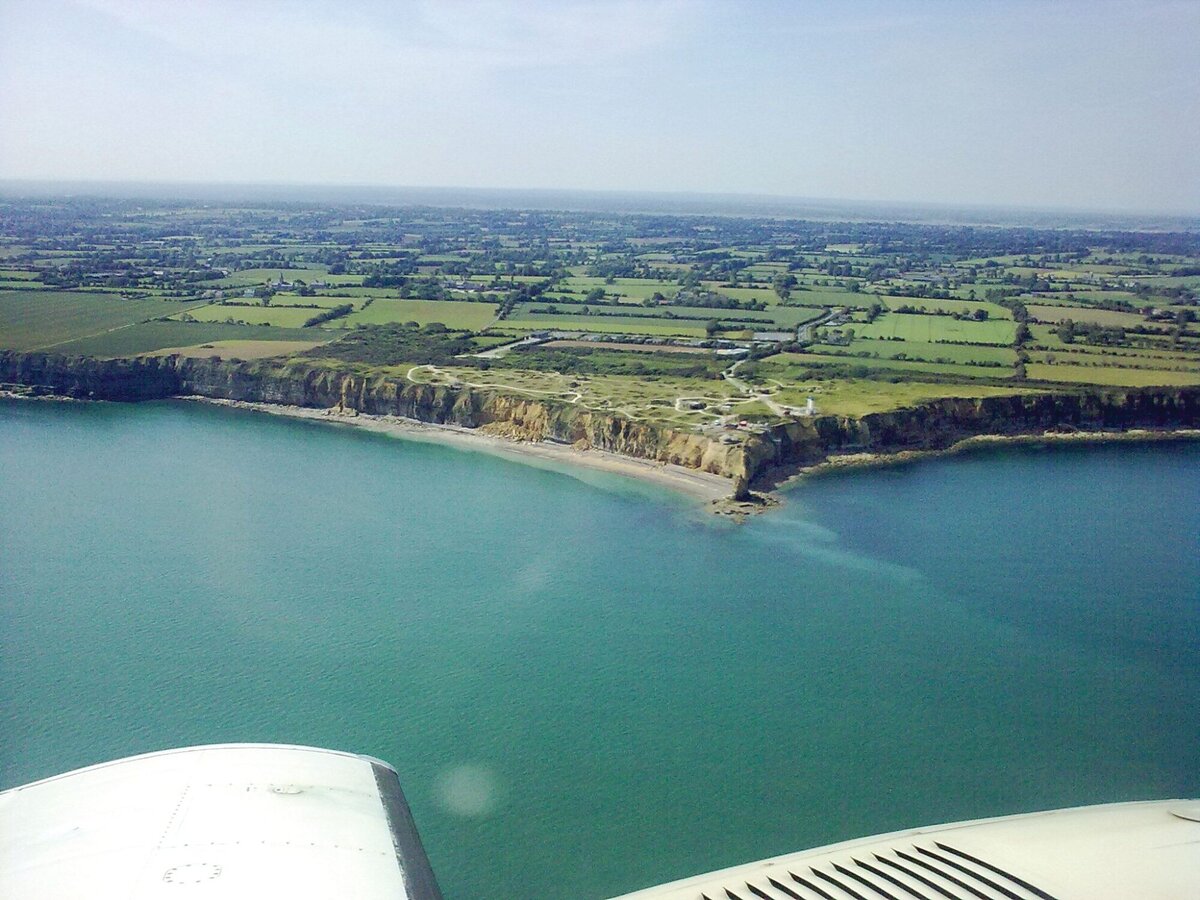 Современное фото мыса Pointe du Hoc. Рейнджеры высаживались по нашу левую руку от мыса. По плану они должны были высаживаться с обоих сторон мыса. https://warfarehistorynetwork.com/article/the-pointe-du-hoc-rangers-a-madmans-d-day-mission/