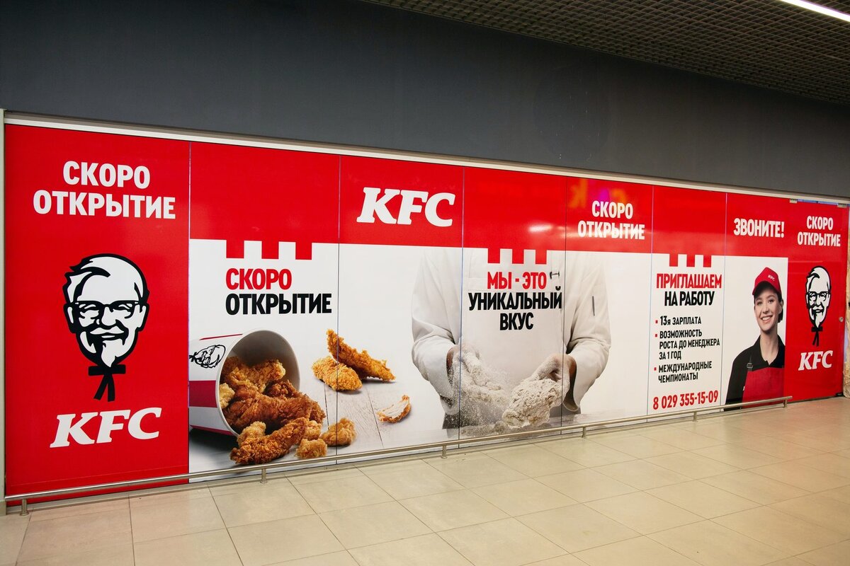 На яркой красно-белой наружной рекламе KFC с изображением полковника Сандерса, жареного куриного филе и сотрудника в форме, анонсируется скорое открытие ресторана и предлагается вакансия с возможностью карьерного роста. 