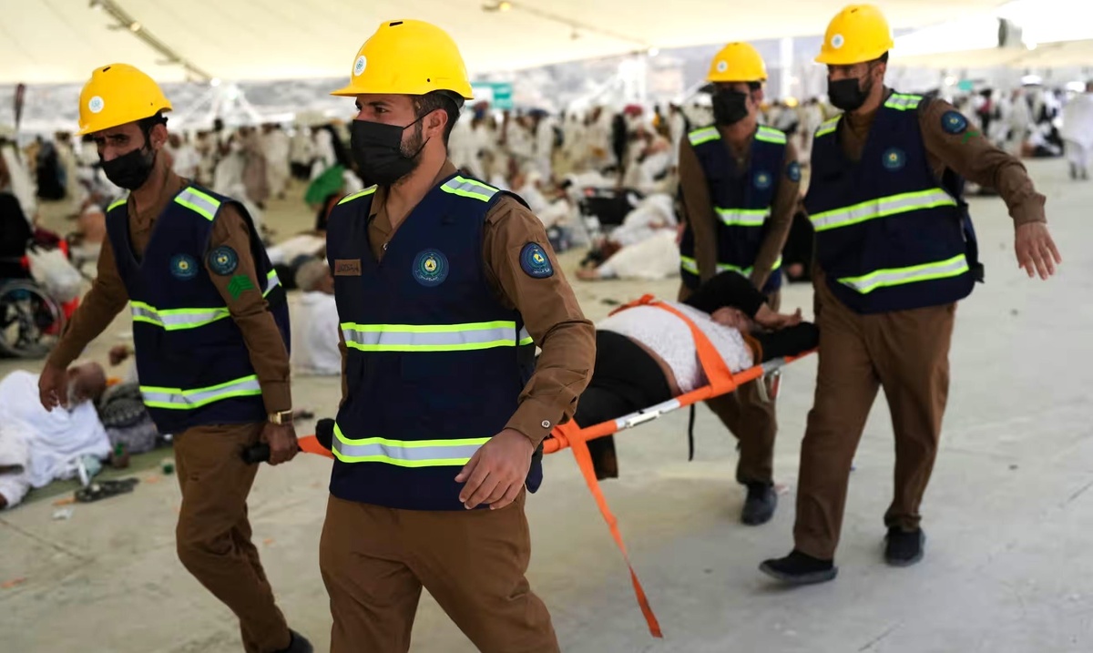 Спасатели уносят женщину, которой стало плохо во время хаджа