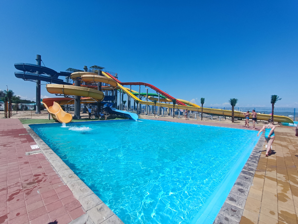 Панорамный вид на аквапарк Немо с разноцветными горками, бассейнами и зеленой территорией у моря