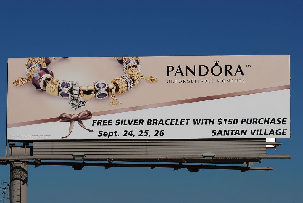 Рекламный билборд ювелирного бренда Pandora предлагает бесплатный серебряный браслет при покупке на сумму $150 и более в торговом центре Сантан Вилладж 24-26 сентября. 