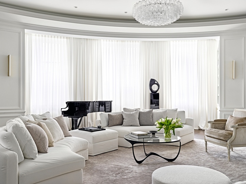 Мягкие очертания полукруглого дивана Harold от Meridiani, обтянутого белоснежной тканью Lelievre, подчеркивают плавный изгиб стен гостиной. Подушки обтянуты тканями Dedar и Pierre Frey. На постаменте — абстрактная скульптура из мрамора Nero Marquina, работа итальянских дизайнеров Francesco Barberini и Nina Alexandra Gunnell. Люстра Poly из муранского стекла, Bella Figura.