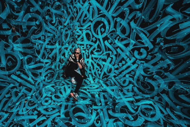 Покрас Лампас на фоне своей работы. Источник: https://www.championat.com/lifestyle/article-3592649-vse-raboty-pokras-lampasa-kalligrafist-iz-peterburga-risunki-pokrasa.html