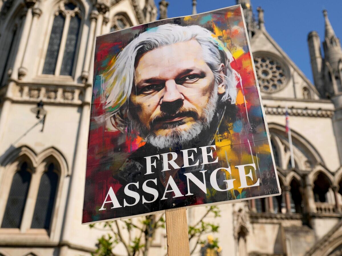    Протестующие держат плакат с портретом Джулиана Ассанжа возле Высокого суда в Лондоне© AP Photo / Kin Cheung