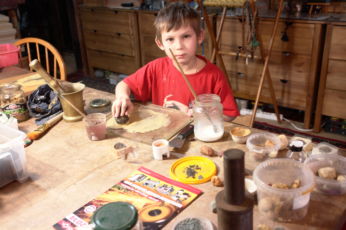Ученик иконописца Георгий растирает минеральные краски курантом на стеклянной платформе. Дом мастерская русского иконописца в Брехово.