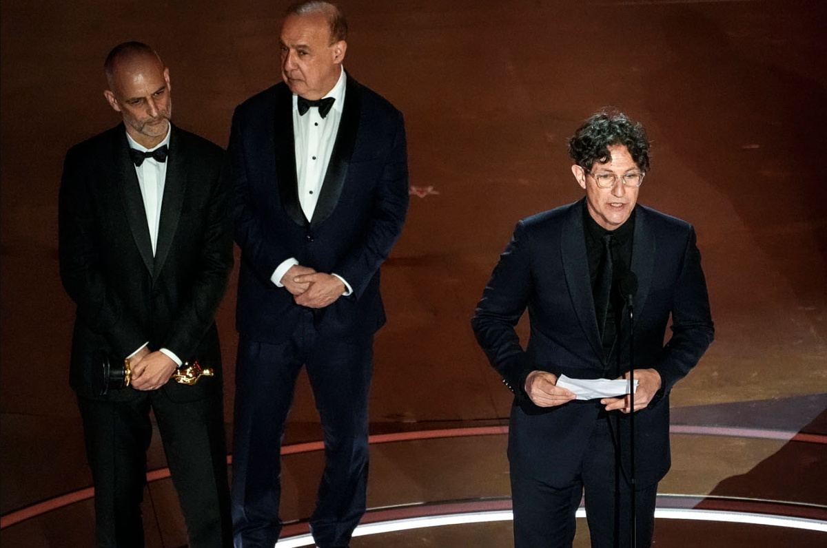 Джонатан Глейзер зачитывает речь на вручении "Оскара"-2024. Рядом с ним - продюсеры Джеймс Уилсон и Леонид Блаватник.