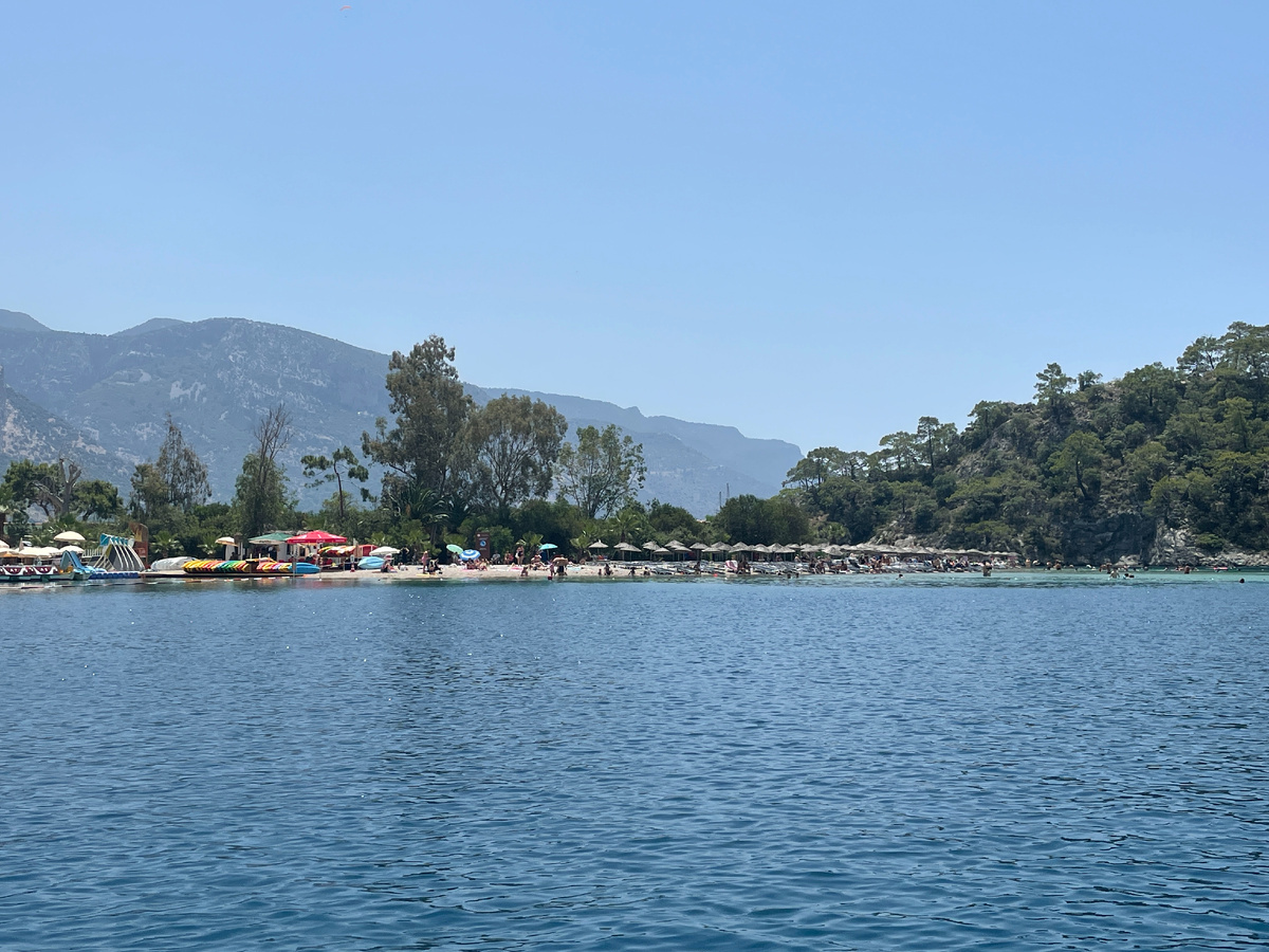 Вид на пляж Голубой лагуны со стороны залива. Слева видна стоянка катамаранов и САП-серфов, справа - ряды пляжных зонтиков.